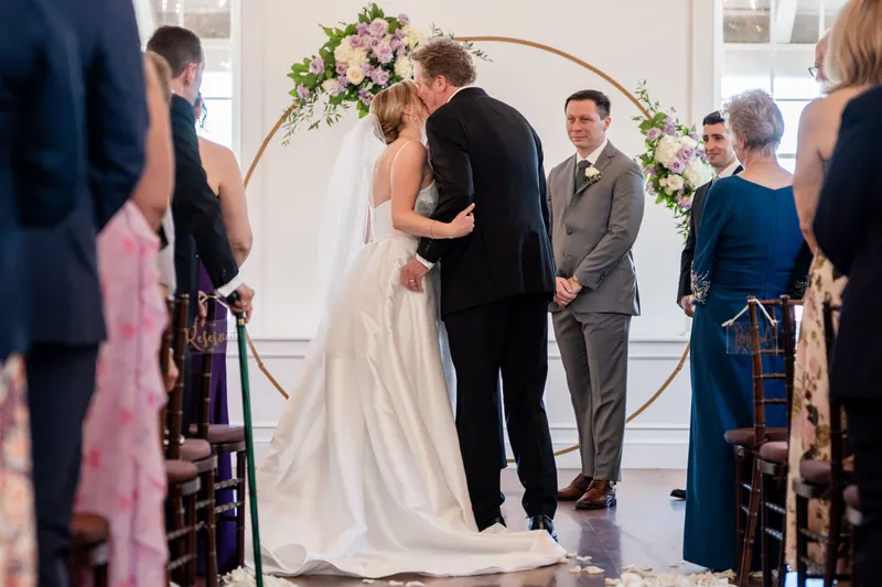 Sarah and Tim exchange vows beneath a floral arch as officiant and family witness their ceremony.