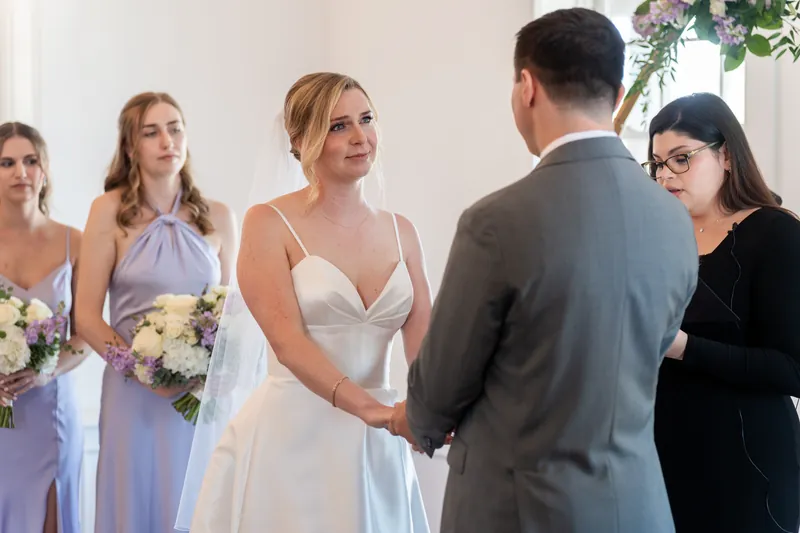 Tim shakes hands with Sarah's mother as Sarah stands beside him, with bridesmaids in lavender dresses nearby.