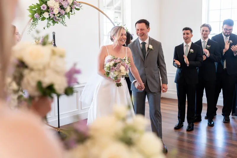 Sarah and Tim walk down the aisle at Villa Blanca hand in hand, with groomsmen following behind them.