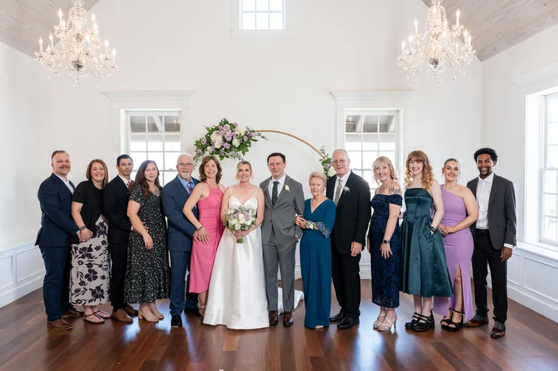 Sarah and Tim pose with their wedding party—family and friends in formal attire—in the chapel.