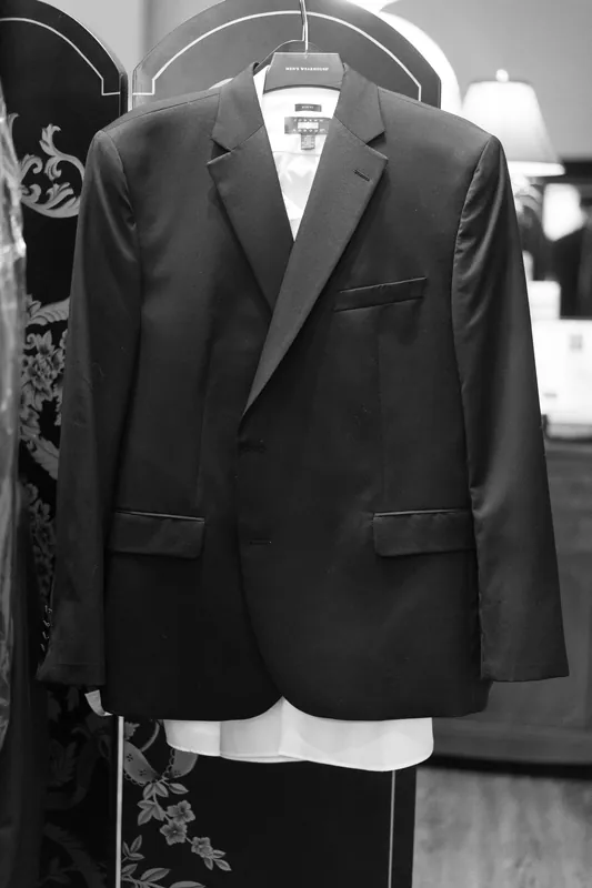 Black tuxedo jacket with peaked lapels hangs on a hanger against an ornate backdrop at Casa Monica Resort & Spa.