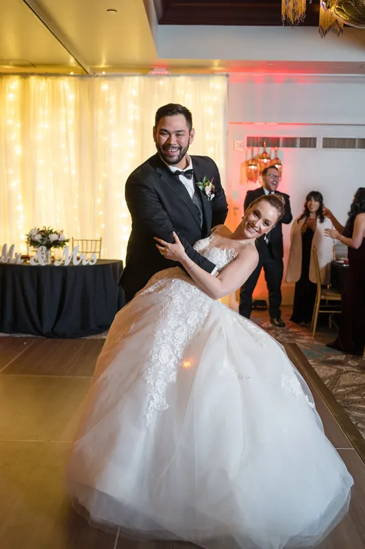 Michael dips Simone low during their first dance on the ballroom floor, her tulle skirt sweeping as they move.