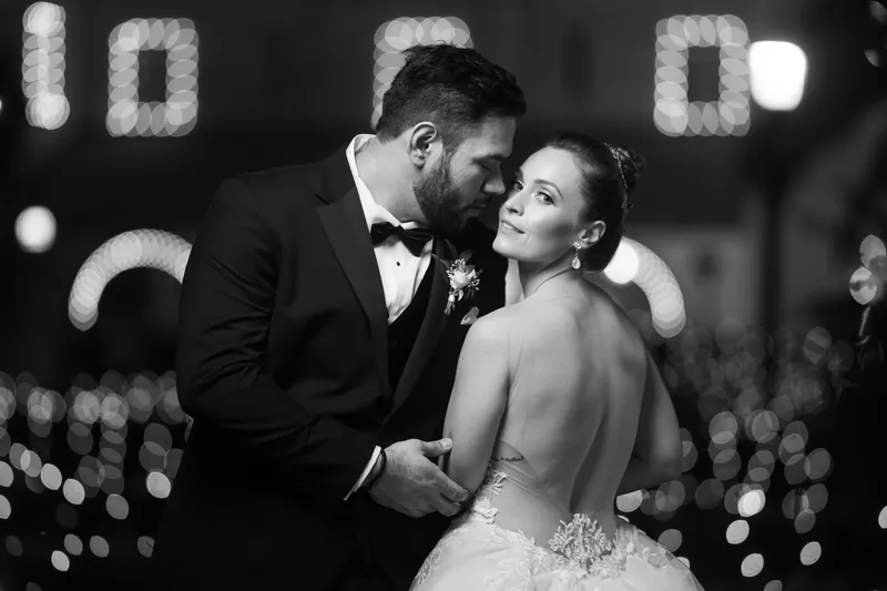 In black and white, Michael and Simone lean close amid soft bokeh lights at their reception venue.