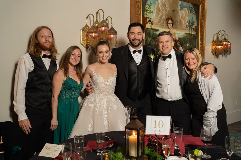 Michael and Simone pose with five family members in formal attire at the decorated reception table.