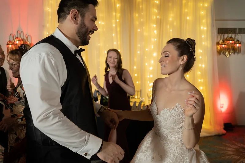 Michael and Simone face each other on the dance floor, bathed in warm golden lighting from the backdrop behind them.