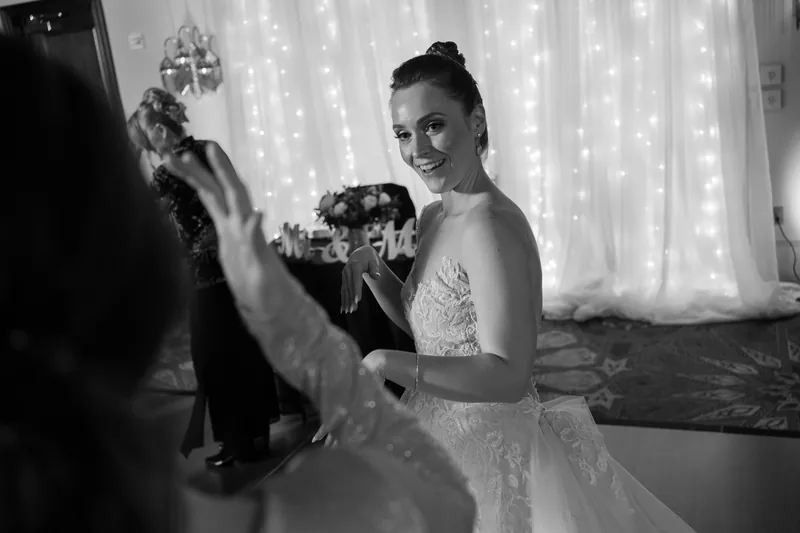 Simone in her beaded gown looks back over her shoulder during their first dance, captured in black and white.