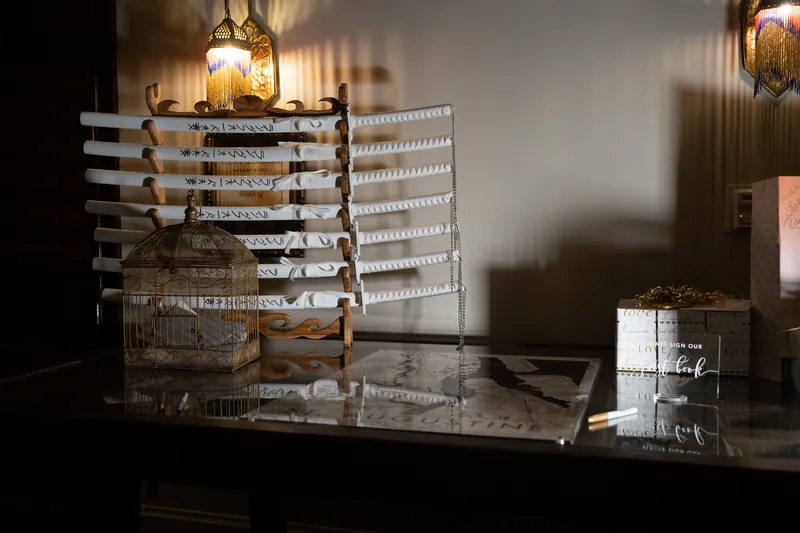 Tiered seating chart and wedding stationery display on a black table under pendant lighting.