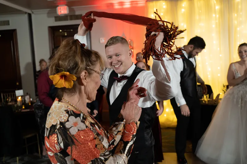 Michael laughs while dancing with a guest holding fabric overhead at the reception.