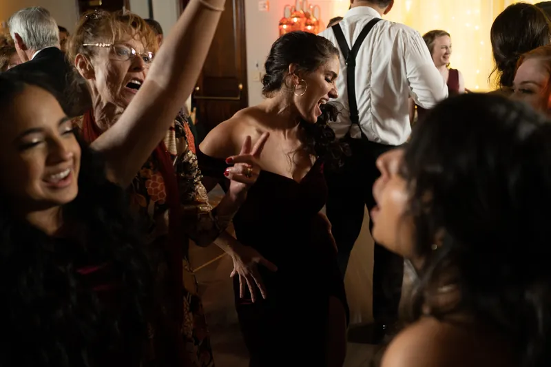 Simone dances surrounded by wedding guests in warm lighting at the reception hall.