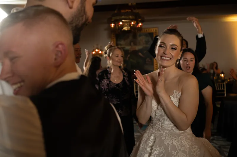 Simone claps and smiles during dancing as guests surround her on the dance floor.