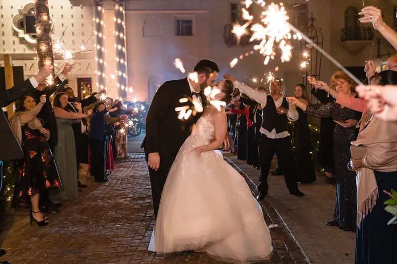 Simone and Michael kiss as guests hold sparklers around them at Casa Monica Resort & Spa.