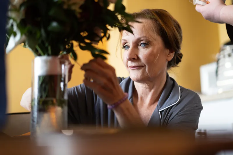 A woman in a gray shirt reaches toward greenery in a vase at Casa Monica Resort & Spa, St. Augustine.
