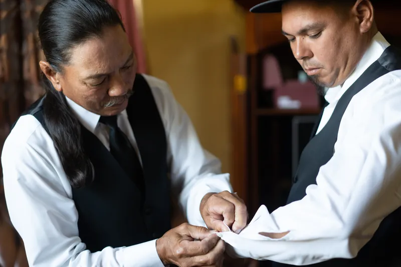 Simone and Michael exchange vows indoors, both wearing formal attire and focused on each other.