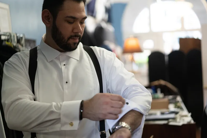 Michael fastens his cufflink in a white dress shirt and black suspenders at Casa Monica Resort & Spa.