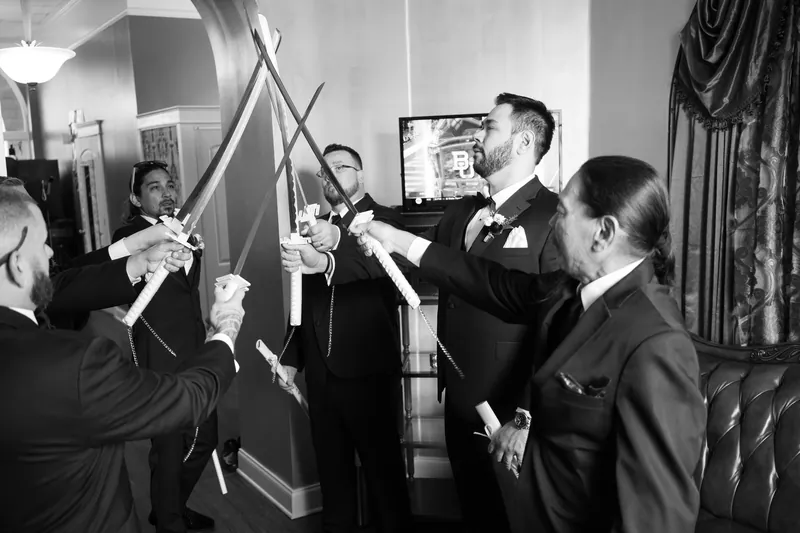 Groomsmen in formal black suits raise champagne glasses in a toast at Casa Monica Resort & Spa.