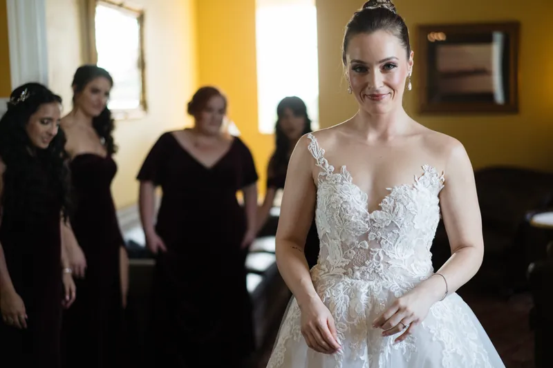 Simone stands in an ornate beaded white gown while attendants adjust her dress behind her.
