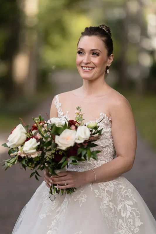Simone holds a bouquet of white roses and burgundy blooms, smiling outdoors at Casa Monica.