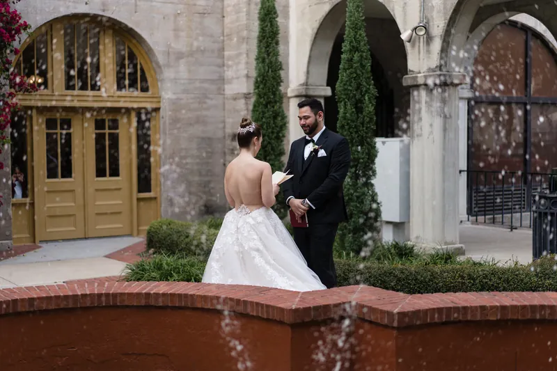Simone and Michael stand by a fountain in the resort courtyard, surrounded by ivy-draped arches and flowering vines.