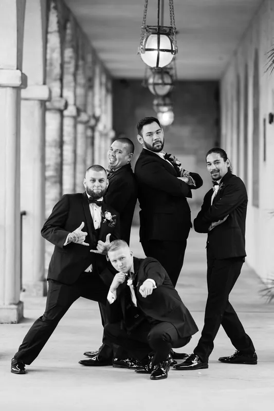Michael and four attendants playfully pose on the colonnade, one kneeling in front in a black and white candid moment.