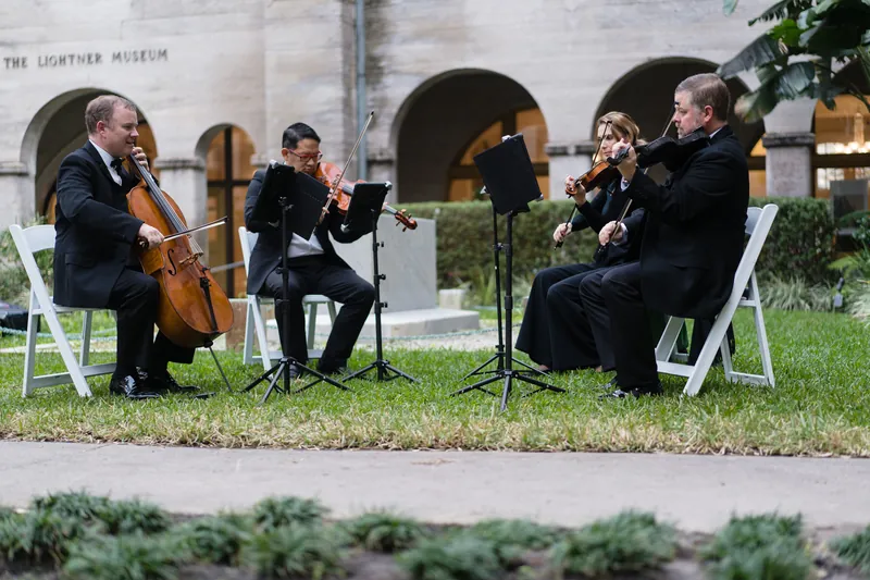 String musicians perform on the lawn with Spanish colonial architecture visible in the background at the resort.