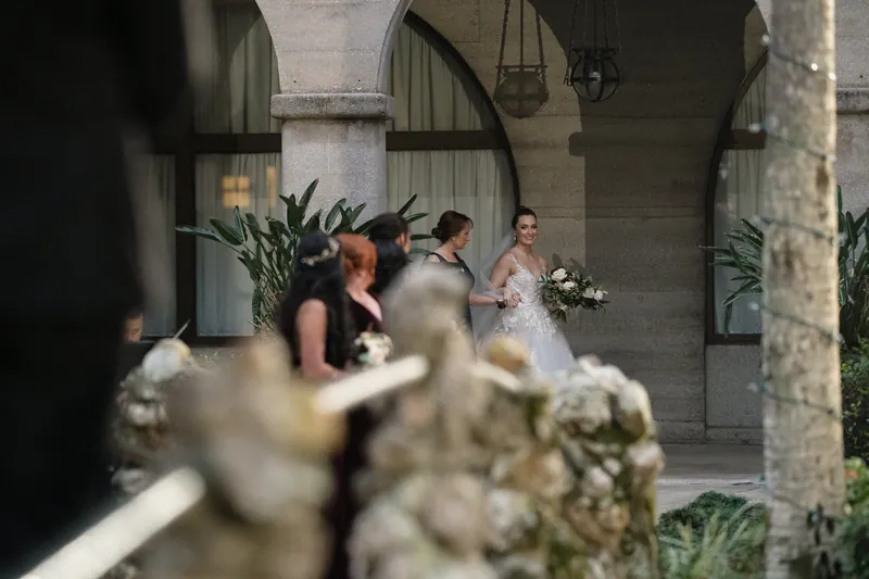 Attendants gather near the arches as ceremony preparations unfold at Casa Monica's colonnade.