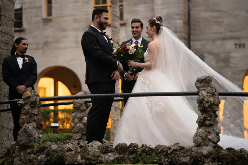 Michael and Simone exchange vows on a stone balcony overlooking the illuminated courtyard below.