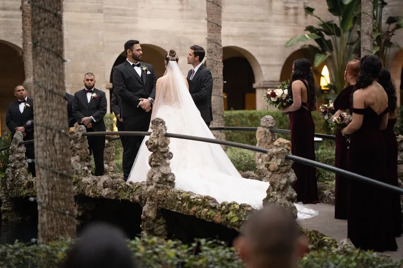 The couple stands together during their ceremony as wedding guests witness the moment on the terrace.