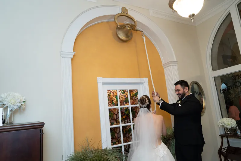 An officiant gestures toward a seating chart while Simone stands nearby in her wedding dress at Casa Monica Resort & Spa.