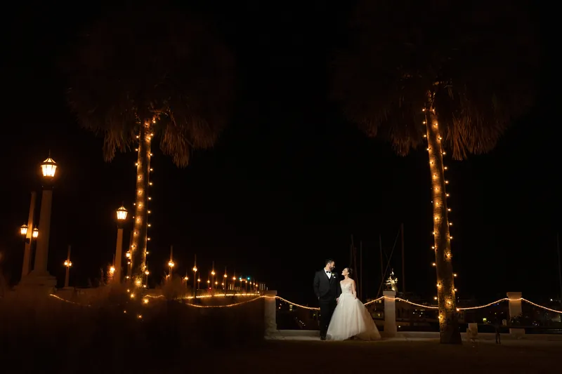 Simone and Michael stand beneath glowing palm trees at Casa Monica Resort & Spa in evening light.