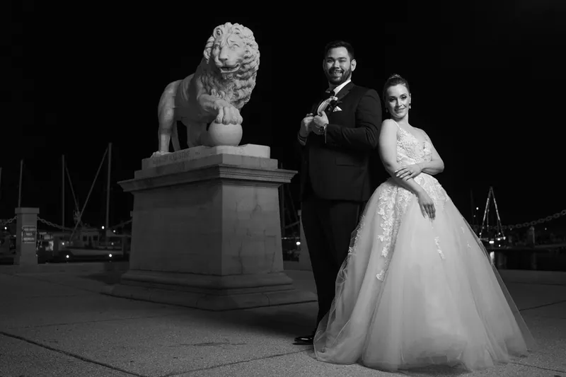 Michael and Simone pose beside a classical bust sculpture in black and white at the resort.