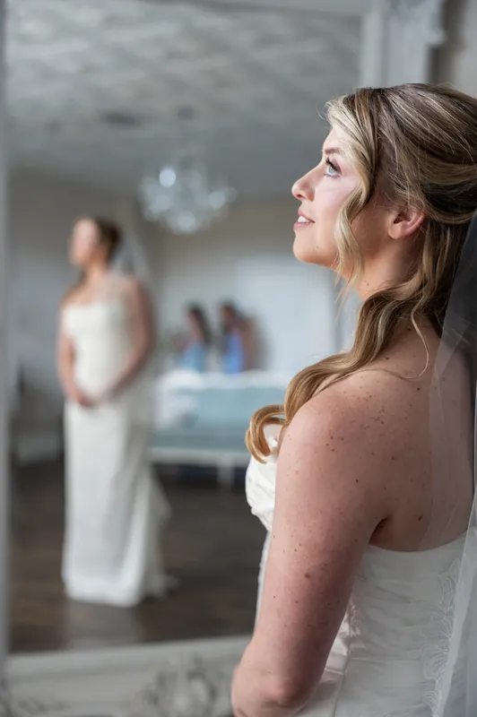 Skye stands in profile wearing a white strapless wedding dress with veil, gazing thoughtfully.