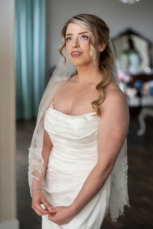 Skye adjusts her white draped strapless gown and lace veil before the ceremony at White Room.