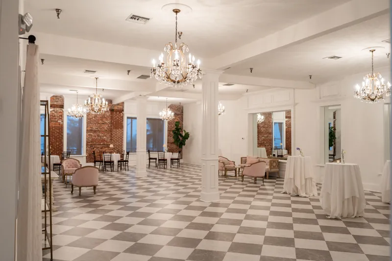 The White Room's grand ballroom features crystal chandeliers, a checkerboard floor, and elegant archways.