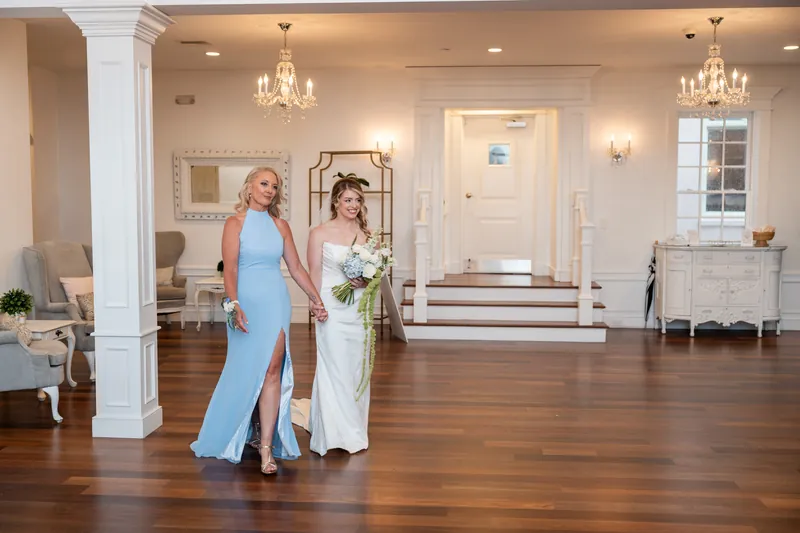 Skye and Elliot walk across the wooden floor of the White Room's grand hall before their ceremony.
