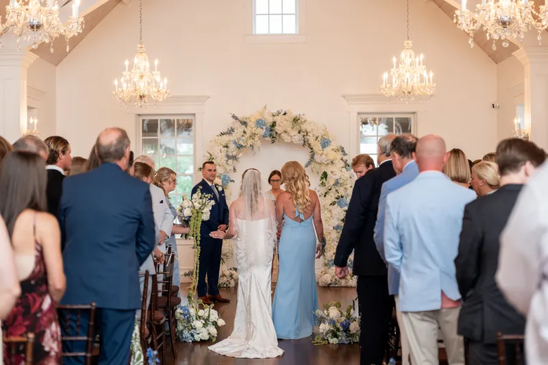 Guests gather for the ceremony in the White Room's elegantly decorated space with floral arch.