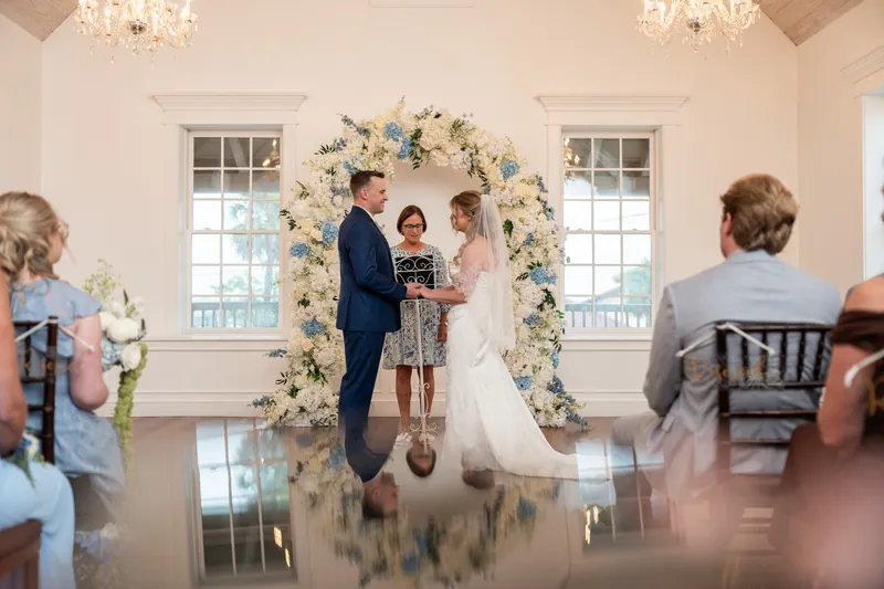 Elliot and Skye exchange vows beneath a cream and blue floral arch at the White Room.