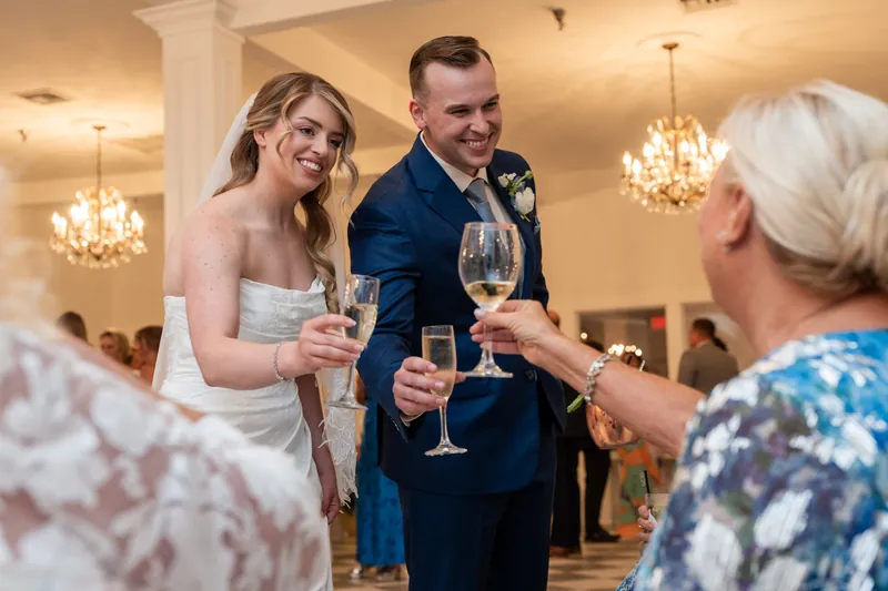 Skye and Elliot toast with guests at The White Room, holding champagne glasses during their celebration.