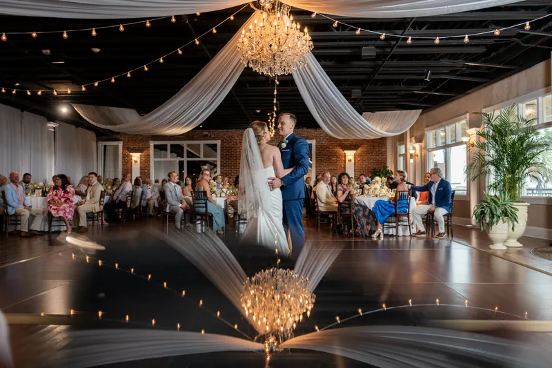 Elliot and Skye's first dance reflected in the polished floor of the White Room as guests watch from surrounding tables.
