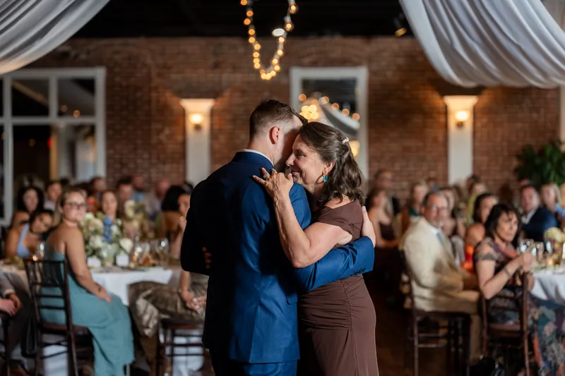 Elliot kisses his mother while guests applaud during the mother-son dance at the White Room reception.