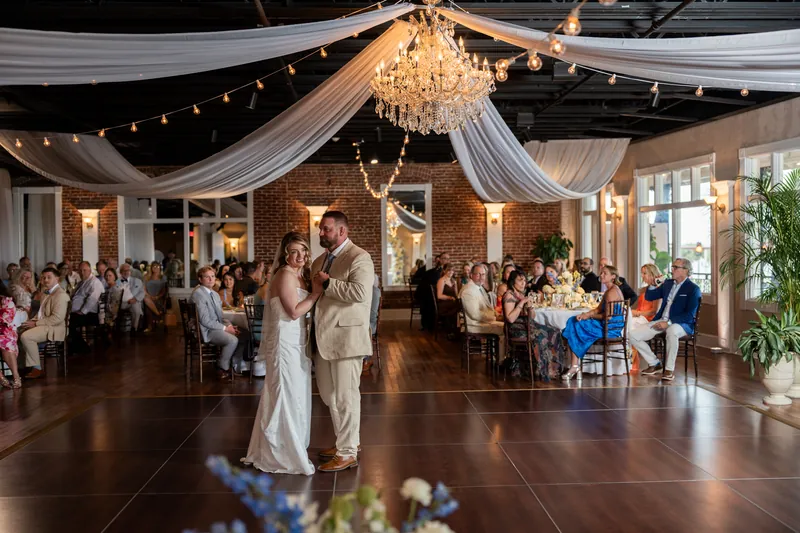 Skye in her white gown dances with a family member as the White Room ballroom glows with string lights and chandeliers.