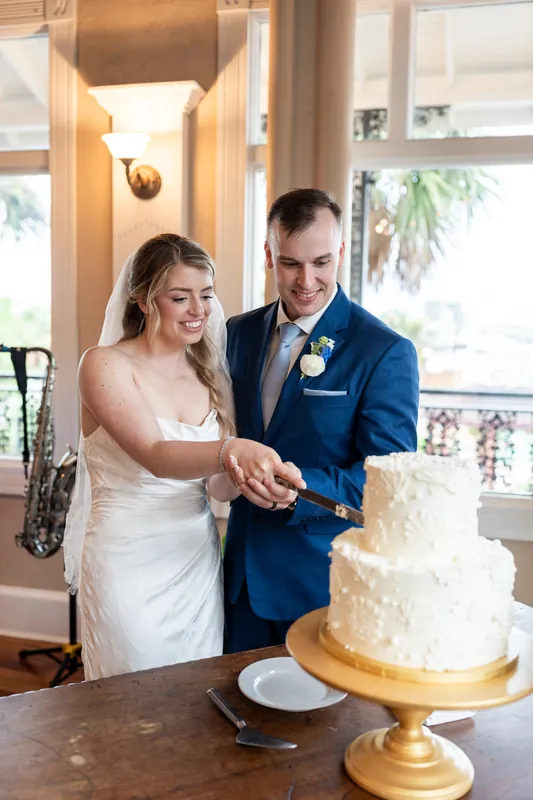 Skye and Elliot cut into their white tiered wedding cake together at White Room.