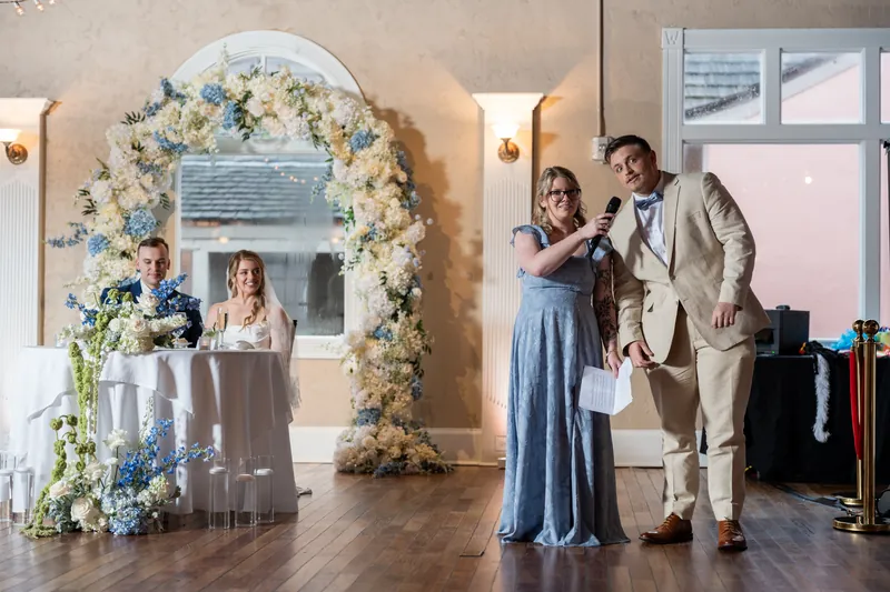 Skye and Elliot stand beneath a floral arch during their ceremony at White Room.