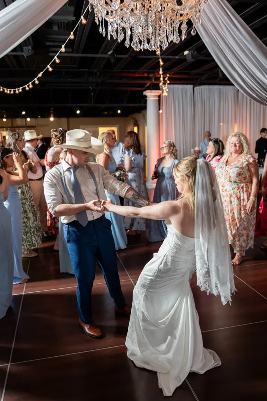 Elliot leads Skye in a dance at White Room while guests watch under a crystal chandelier and draped white ceiling.