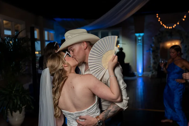 Elliot and Skye dance together, with Skye holding a white fan, under string lights at White Room.