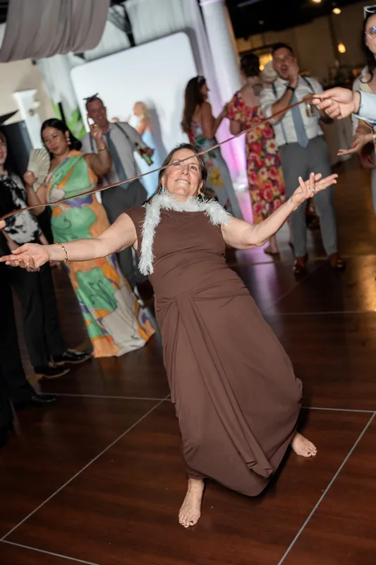 Guest dances barefoot in a brown dress with arms outstretched on the dance floor at White Room.
