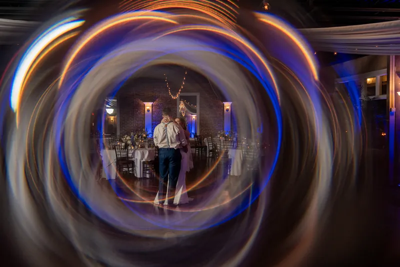 A bride and groom stand together inside a circular light installation at the White Room venue.