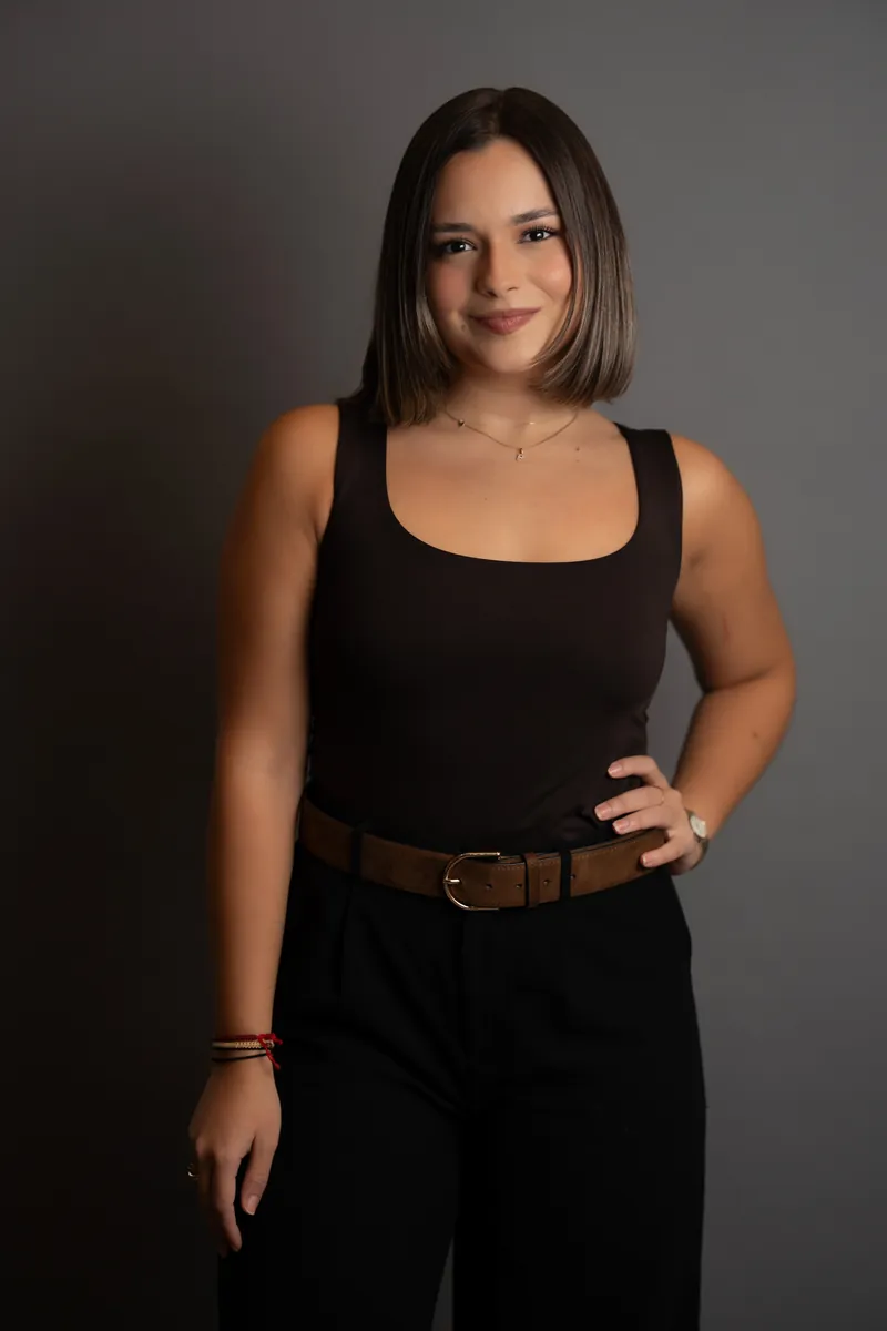 Professional headshot of woman in black outfit against gray studio backdrop