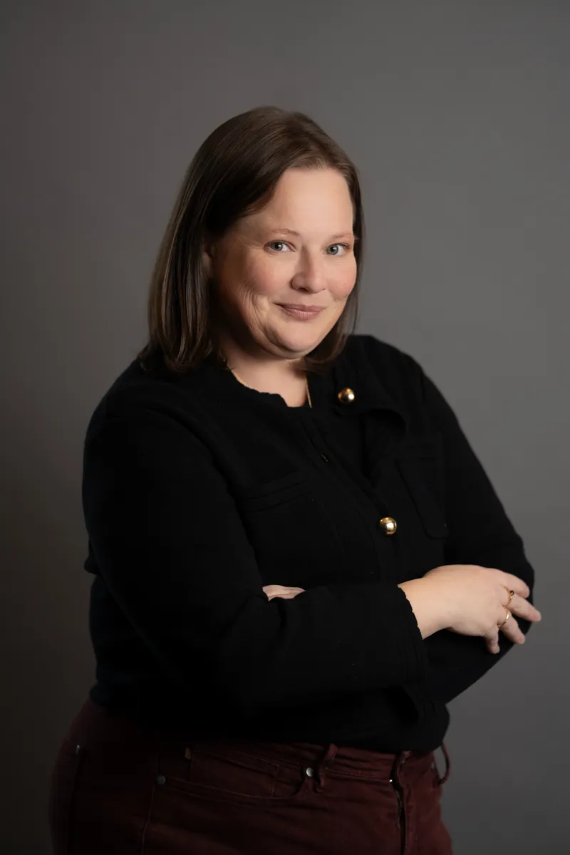 Professional headshot of woman in black jacket with gold buttons
