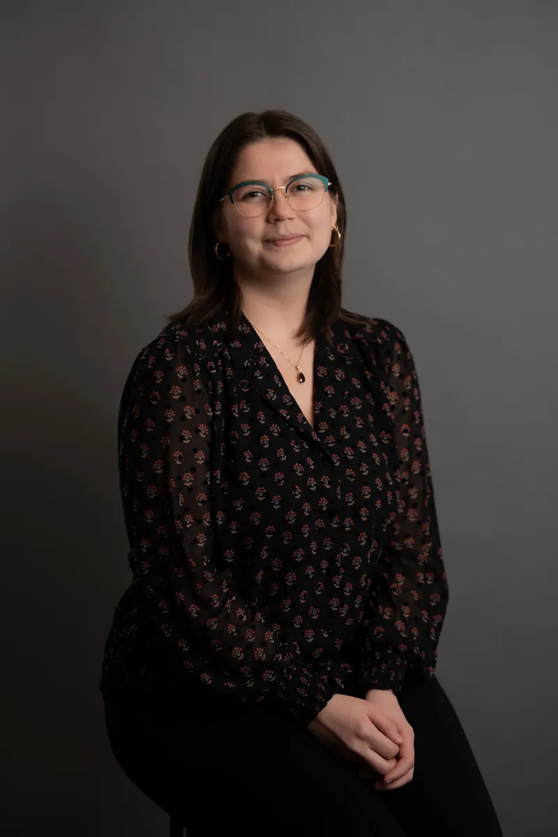 Professional headshot of woman in floral print blouse with glasses
