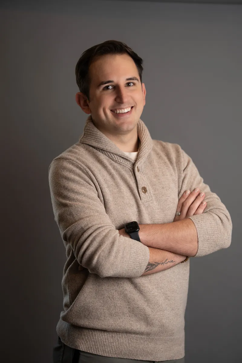 Professional headshot of man in oatmeal sweater with arms crossed